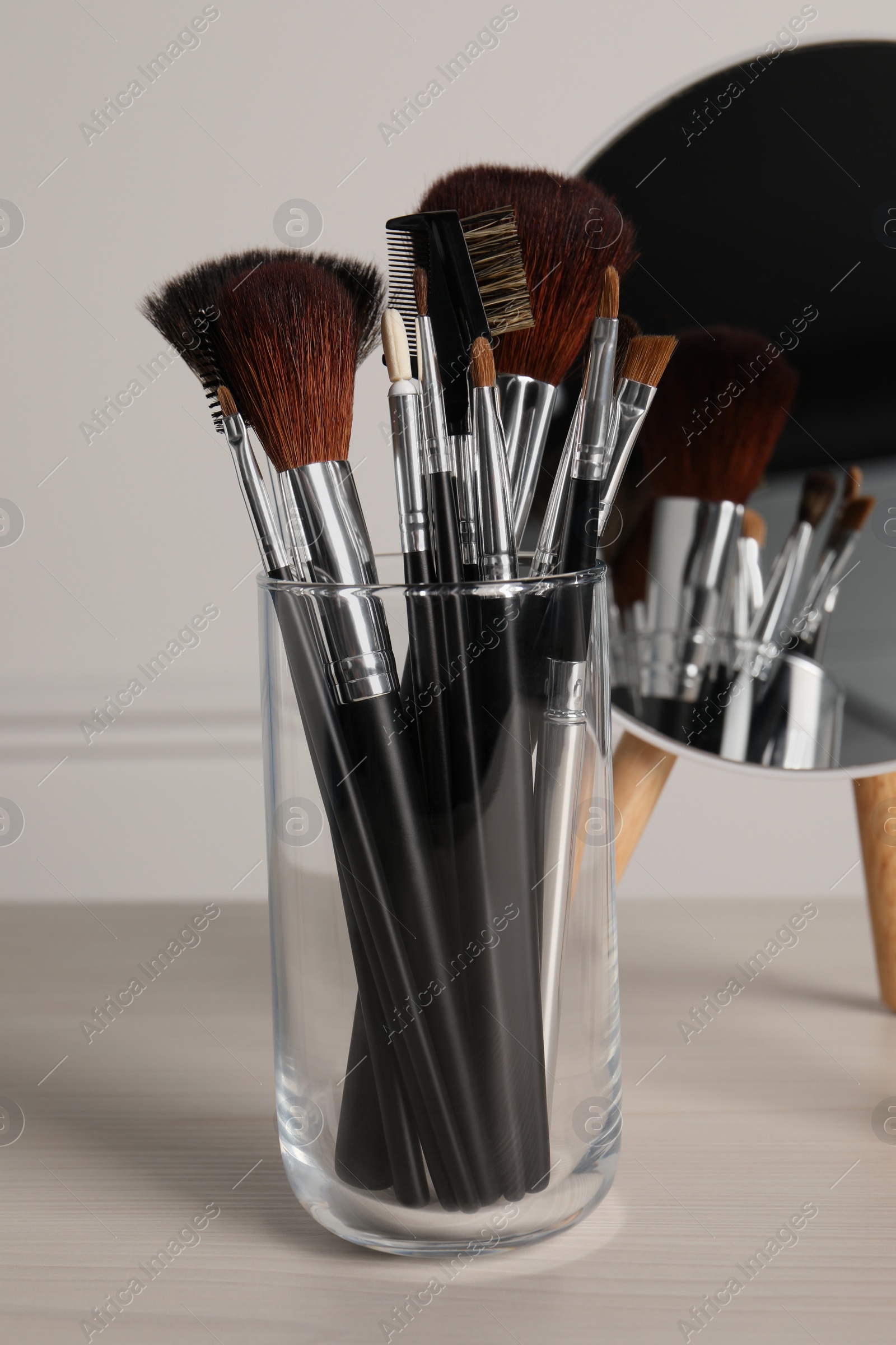 Photo of Set of professional brushes and mirror on wooden table