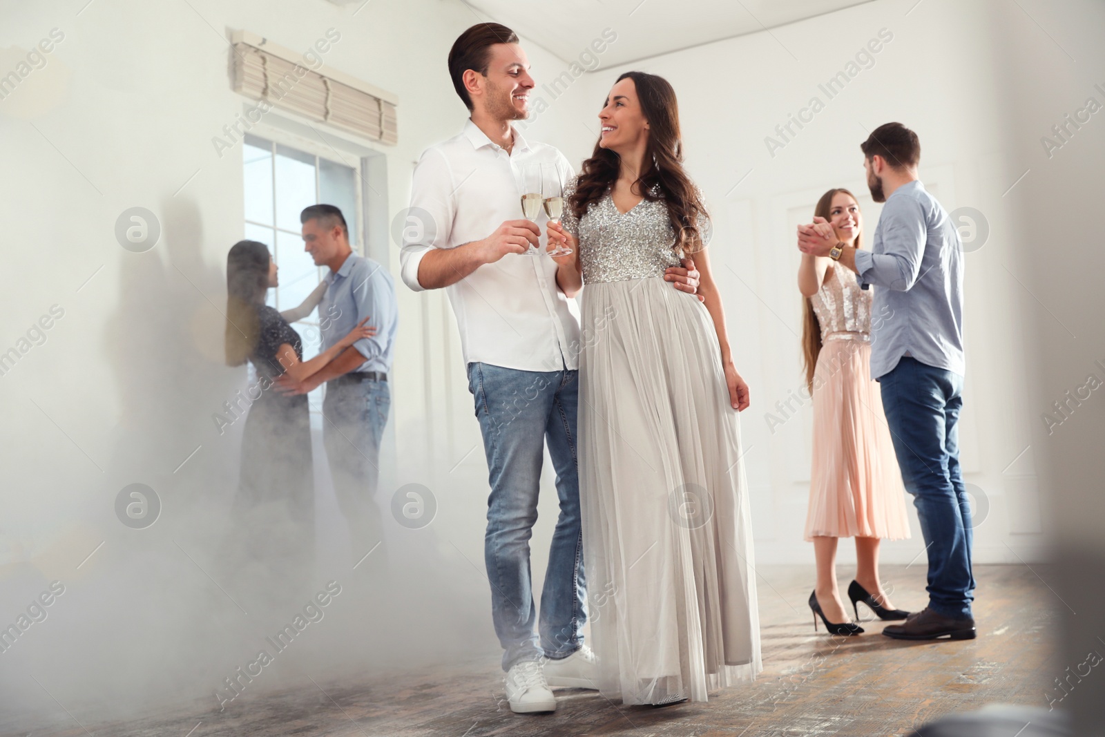 Photo of Lovely young couple with glasses of champagne at dancing party