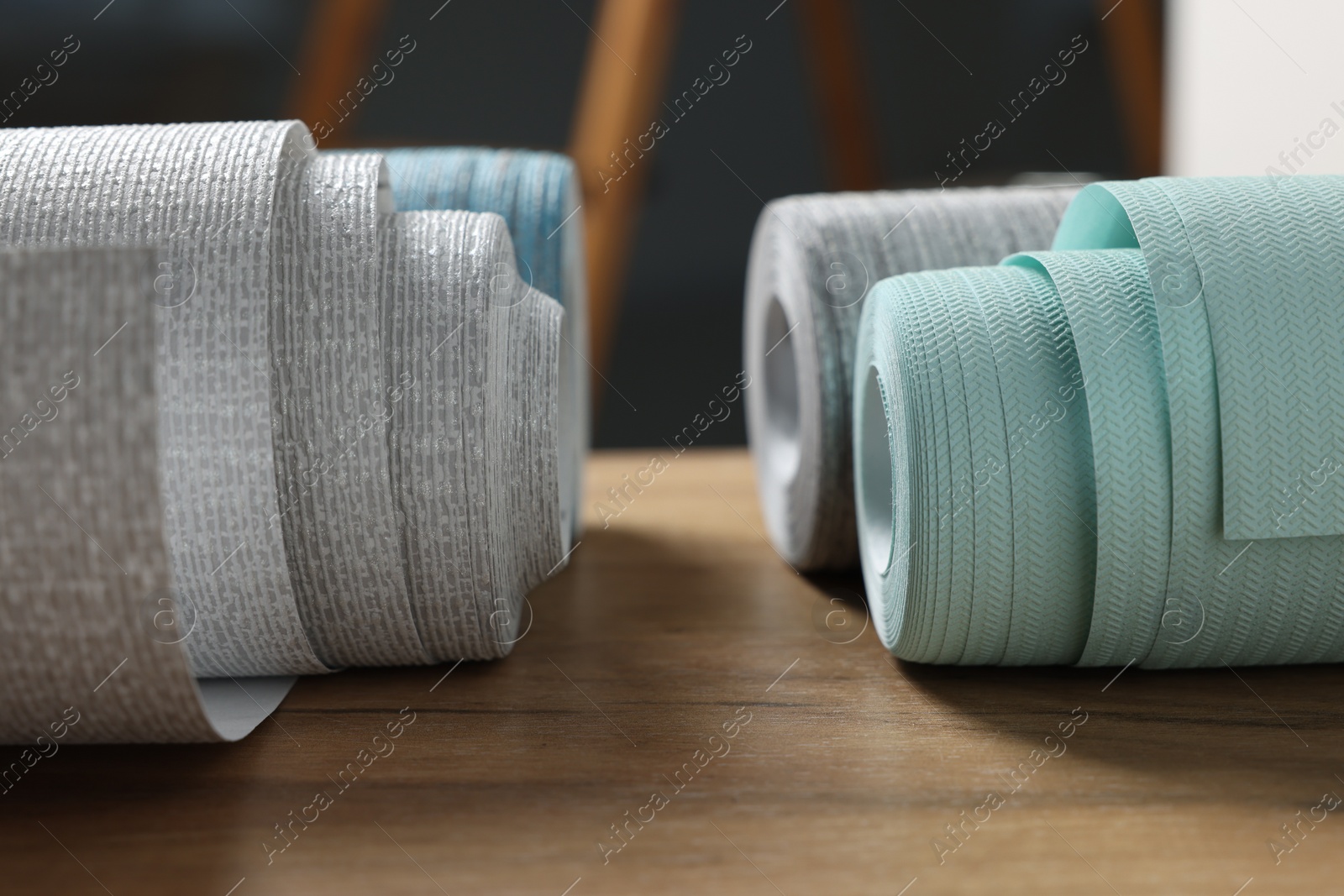 Photo of Different wallpaper rolls on wooden table indoors, closeup