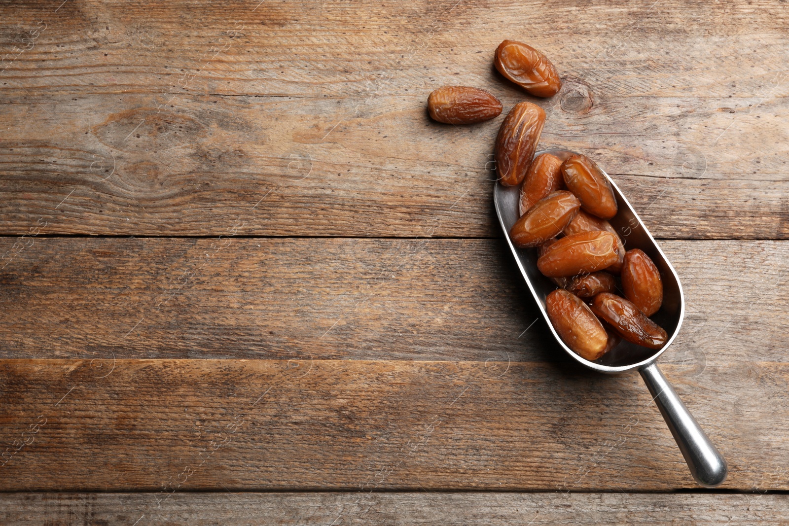 Photo of Scoop with sweet dried date fruits on wooden background, top view. Space for text