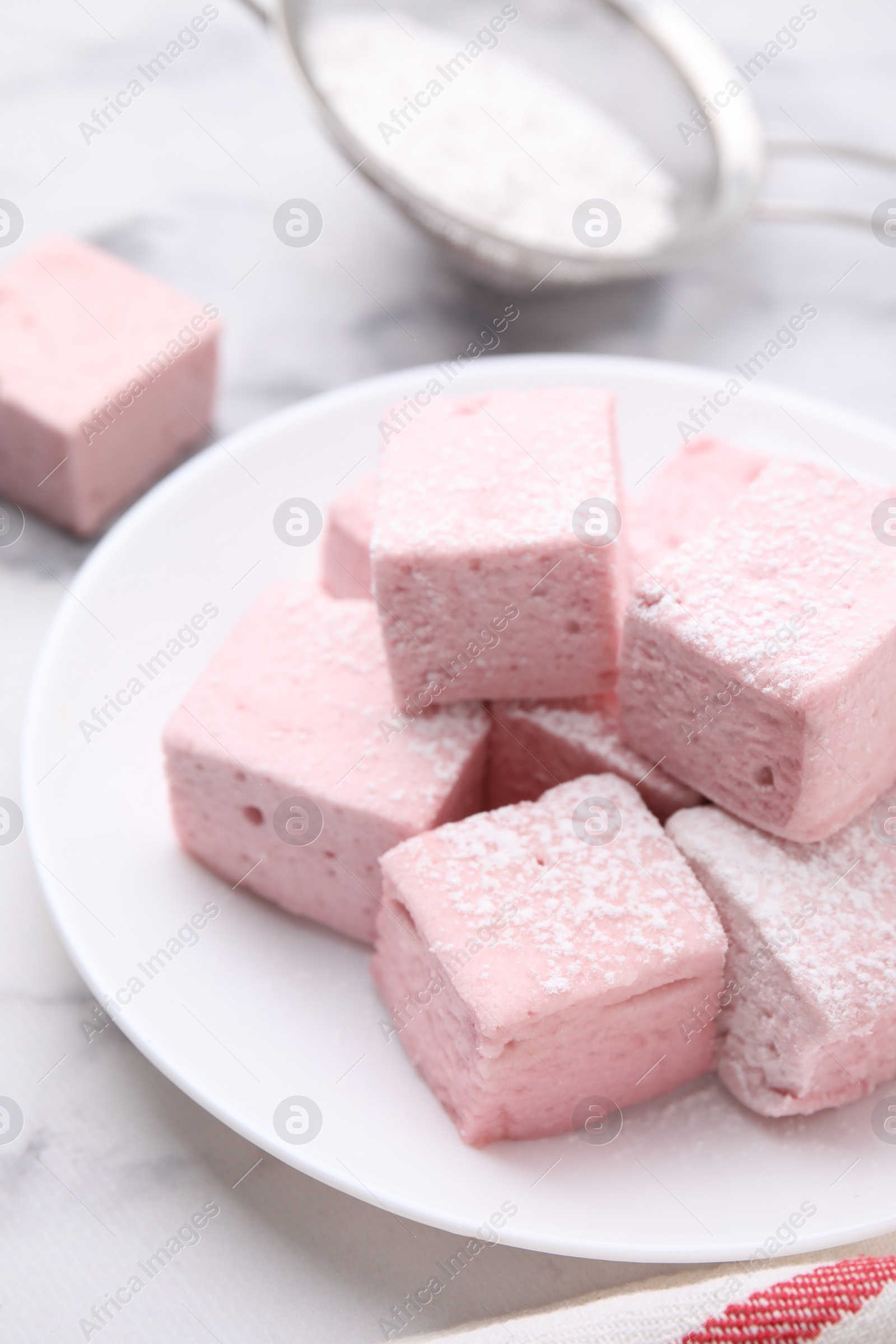 Photo of Plate of delicious sweet marshmallows with powdered sugar on white marble table