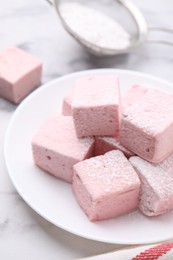 Photo of Plate of delicious sweet marshmallows with powdered sugar on white marble table