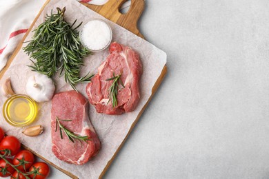 Photo of Fresh raw meat with rosemary, oil, tomatoes and spices on light grey table, flat lay. Space for text