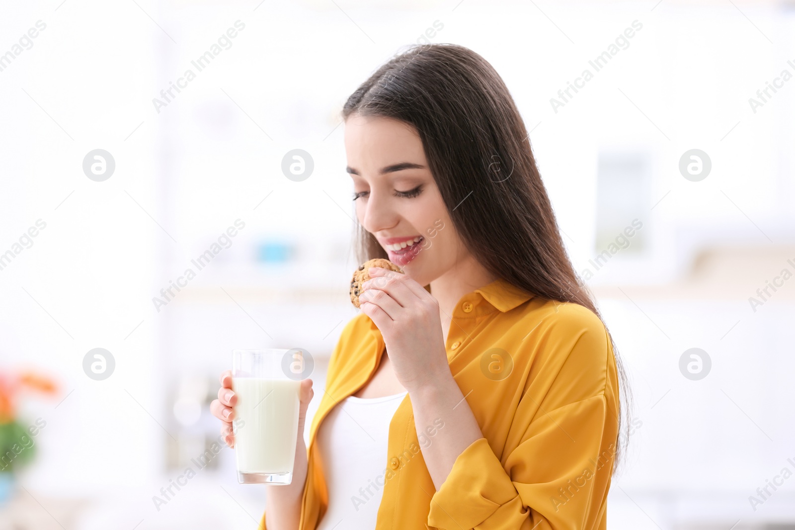 Photo of Beautiful pregnant woman drinking milk and eating cookies at home