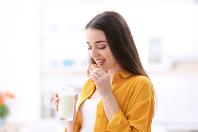 Photo of Beautiful pregnant woman drinking milk and eating cookies at home