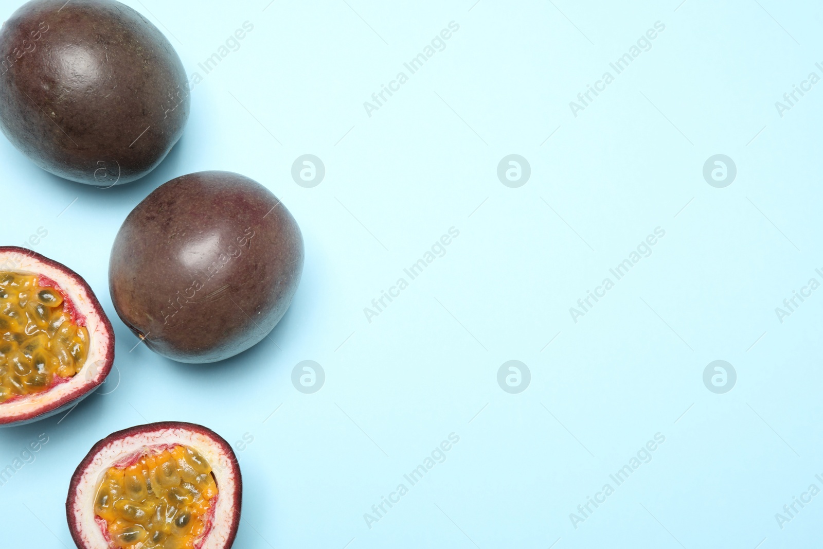 Photo of Fresh ripe passion fruits (maracuyas) on light blue background, flat lay. Space for text