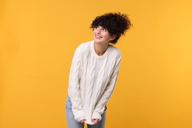 Happy young woman in stylish white sweater on yellow background