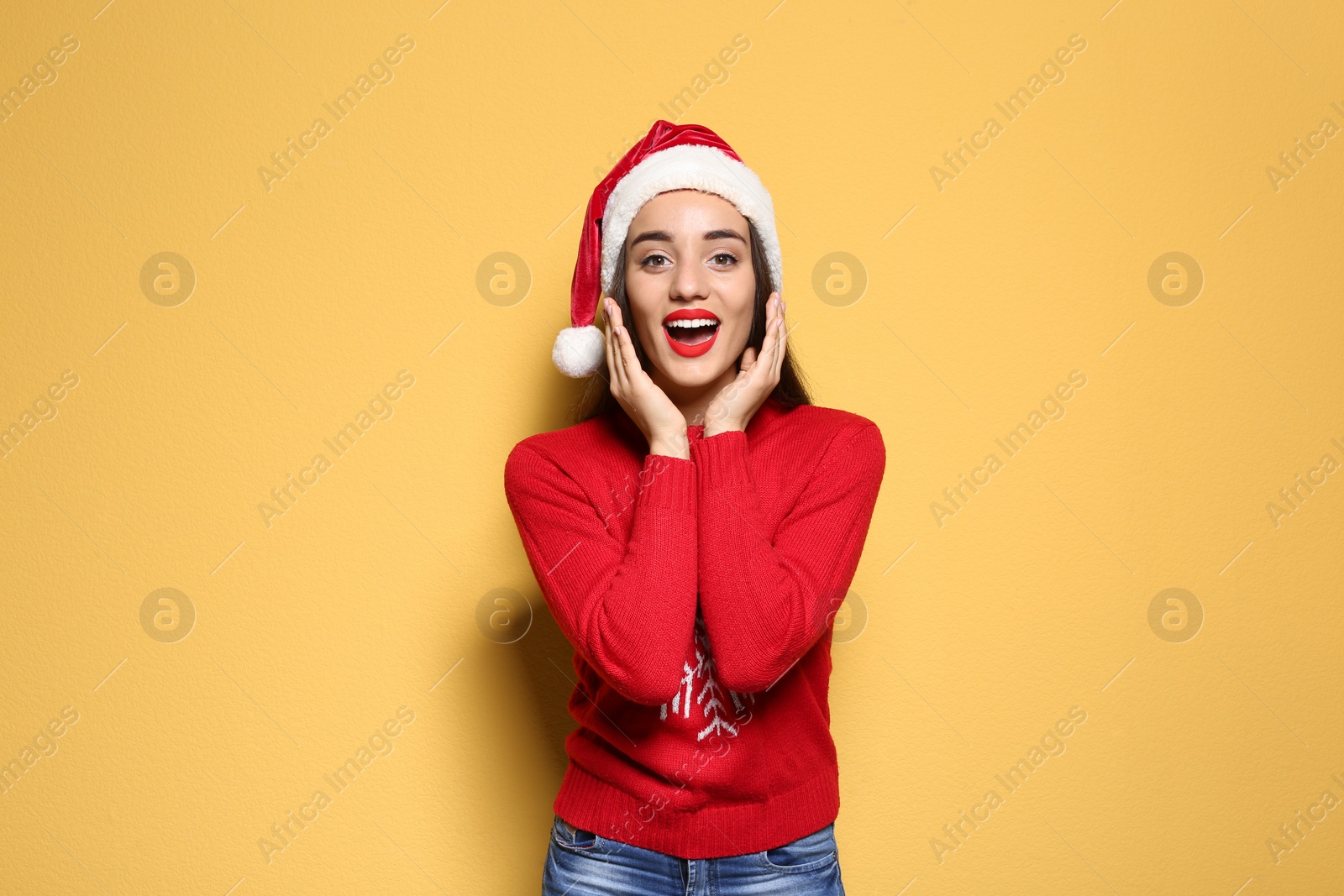 Photo of Young woman in Christmas sweater and hat on color background