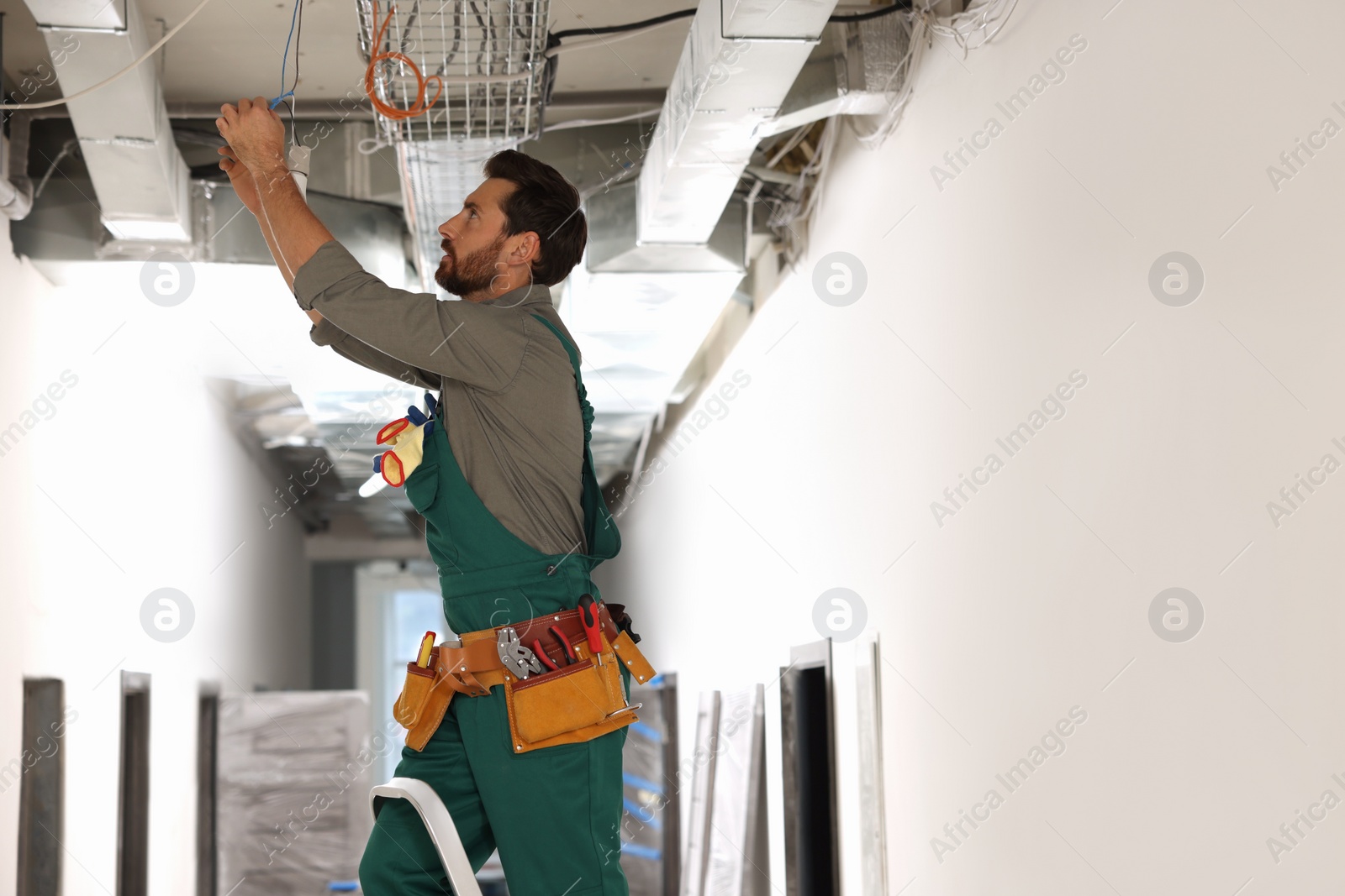 Photo of Electrician with insulting tape repairing ceiling lamp