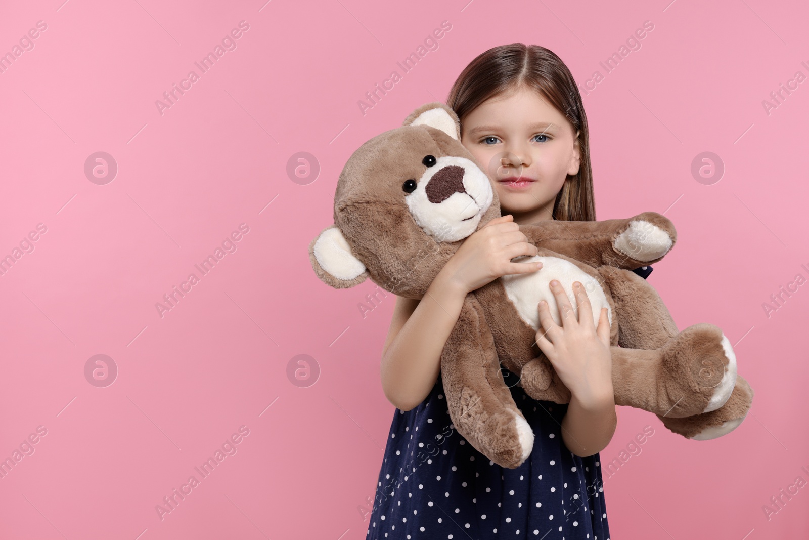 Photo of Cute little girl with teddy bear on pink background. Space for text