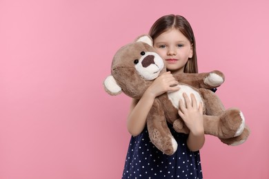 Photo of Cute little girl with teddy bear on pink background. Space for text