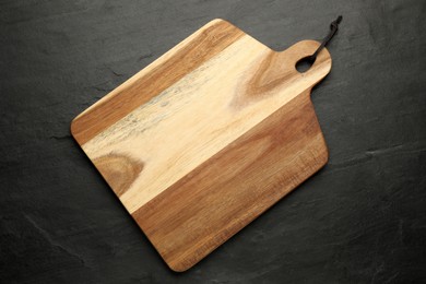 Photo of Wooden cutting board on black table, top view. Cooking utensil