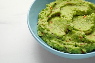 Photo of Bowl with delicious fresh guacamole on white table, closeup. Space for text