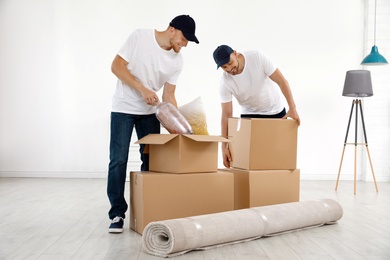 Photo of Moving service employees with cardboard boxes in room