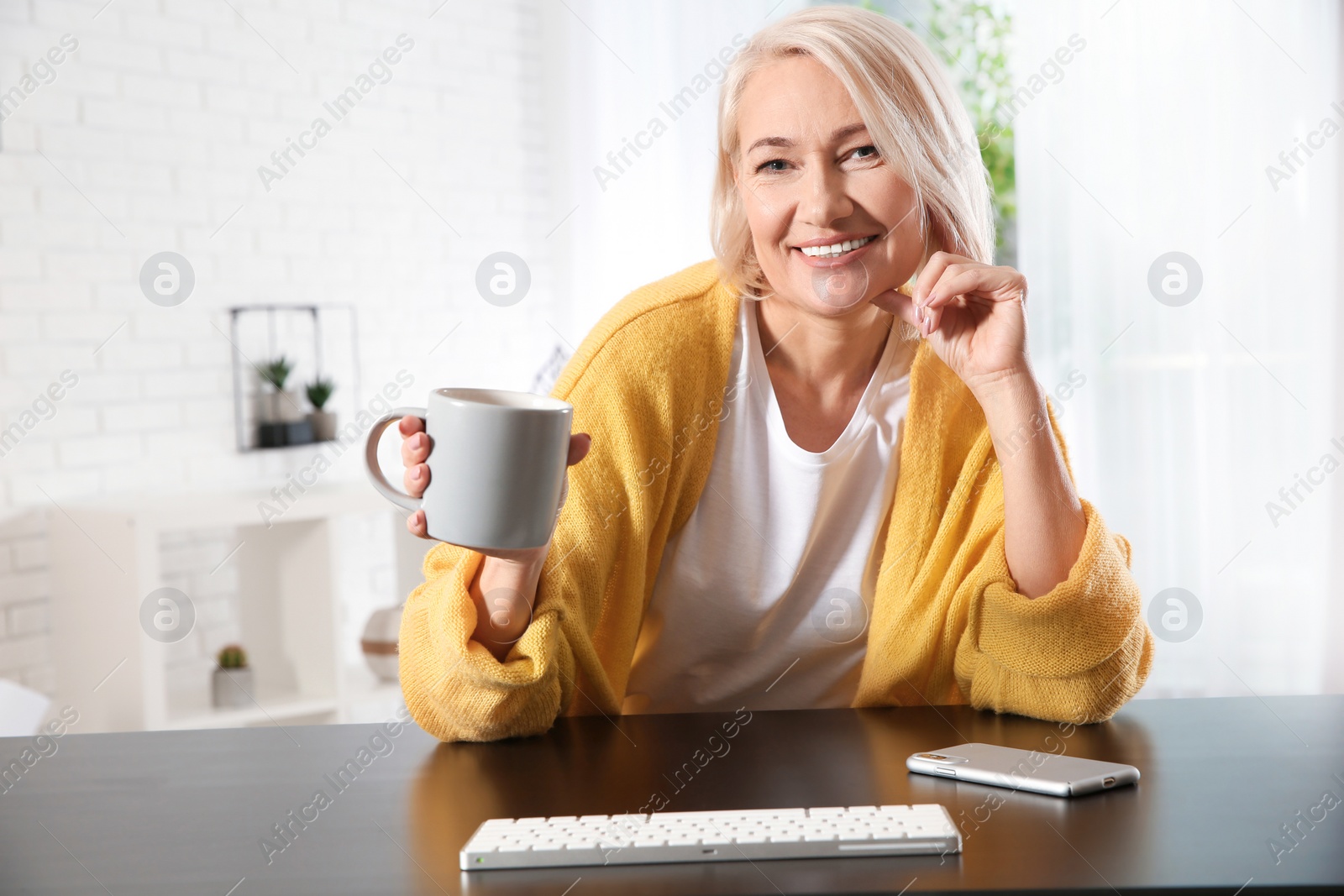 Photo of Mature woman with drink using video chat at home, view from web camera