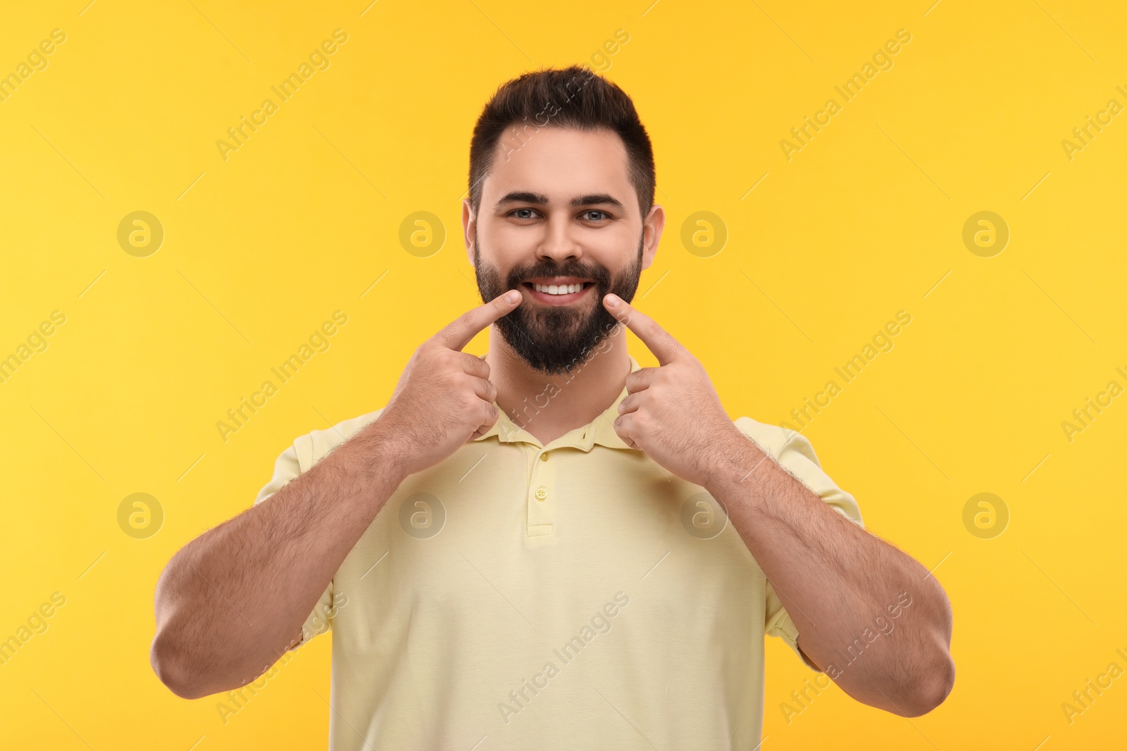Photo of Man showing his clean teeth and smiling on yellow background
