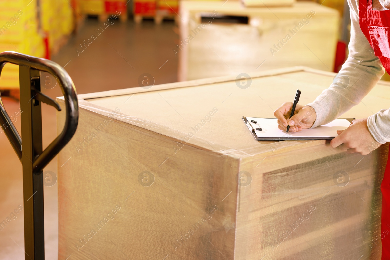 Image of Worker with clipboard near wrapped wooden pallets in warehouse, closeup