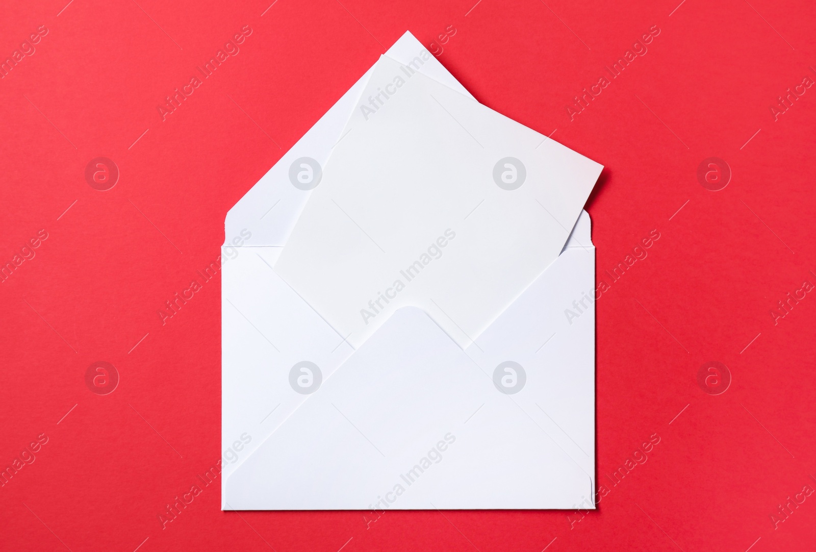 Photo of Letter envelope with card on red background, top view