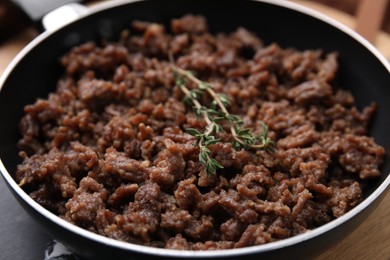 Photo of Fried ground meat and thyme in frying pan on table, closeup