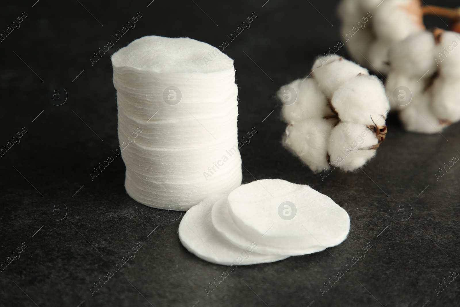 Photo of Cotton pads and flowers on black table, closeup