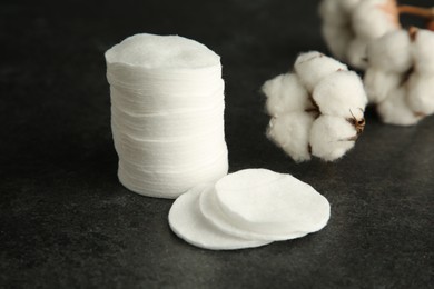 Photo of Cotton pads and flowers on black table, closeup