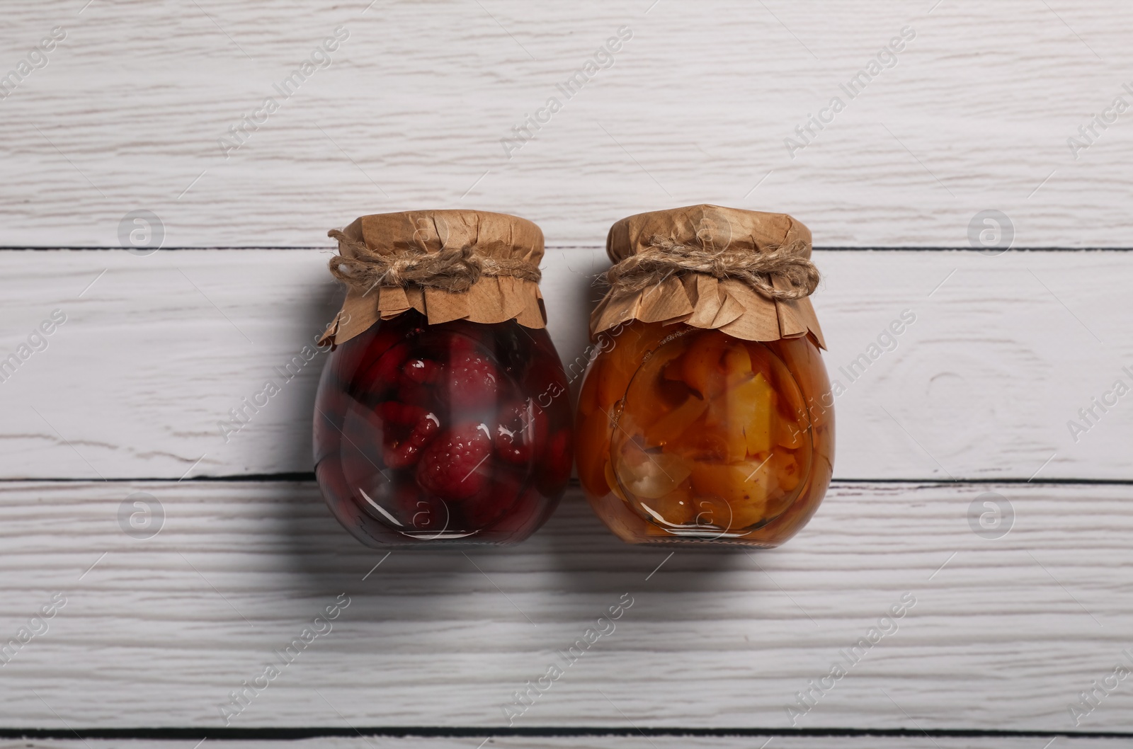 Photo of Jars with pickled fruits on white wooden table, flat lay