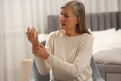 Photo of Mature woman suffering from pain in hand at home, space for text. Rheumatism symptom