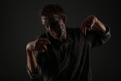 Photo of Scary zombie on dark background. Halloween monster