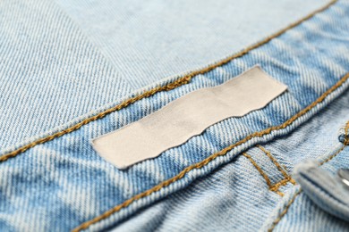 Photo of Blank clothing label on light blue jeans, closeup