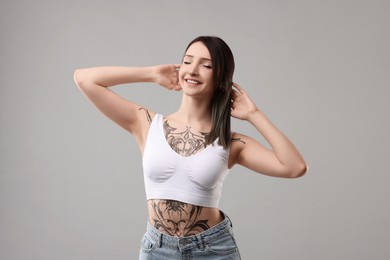 Portrait of smiling tattooed woman on grey background