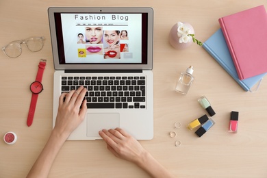 Woman working with fashion blogger site on laptop at table, top view