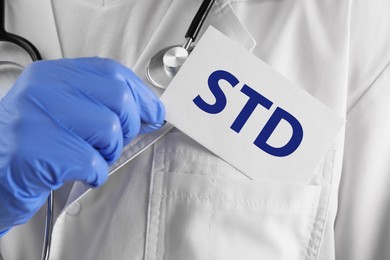 Photo of Doctor holding sheet of paper with abbreviation STD, closeup