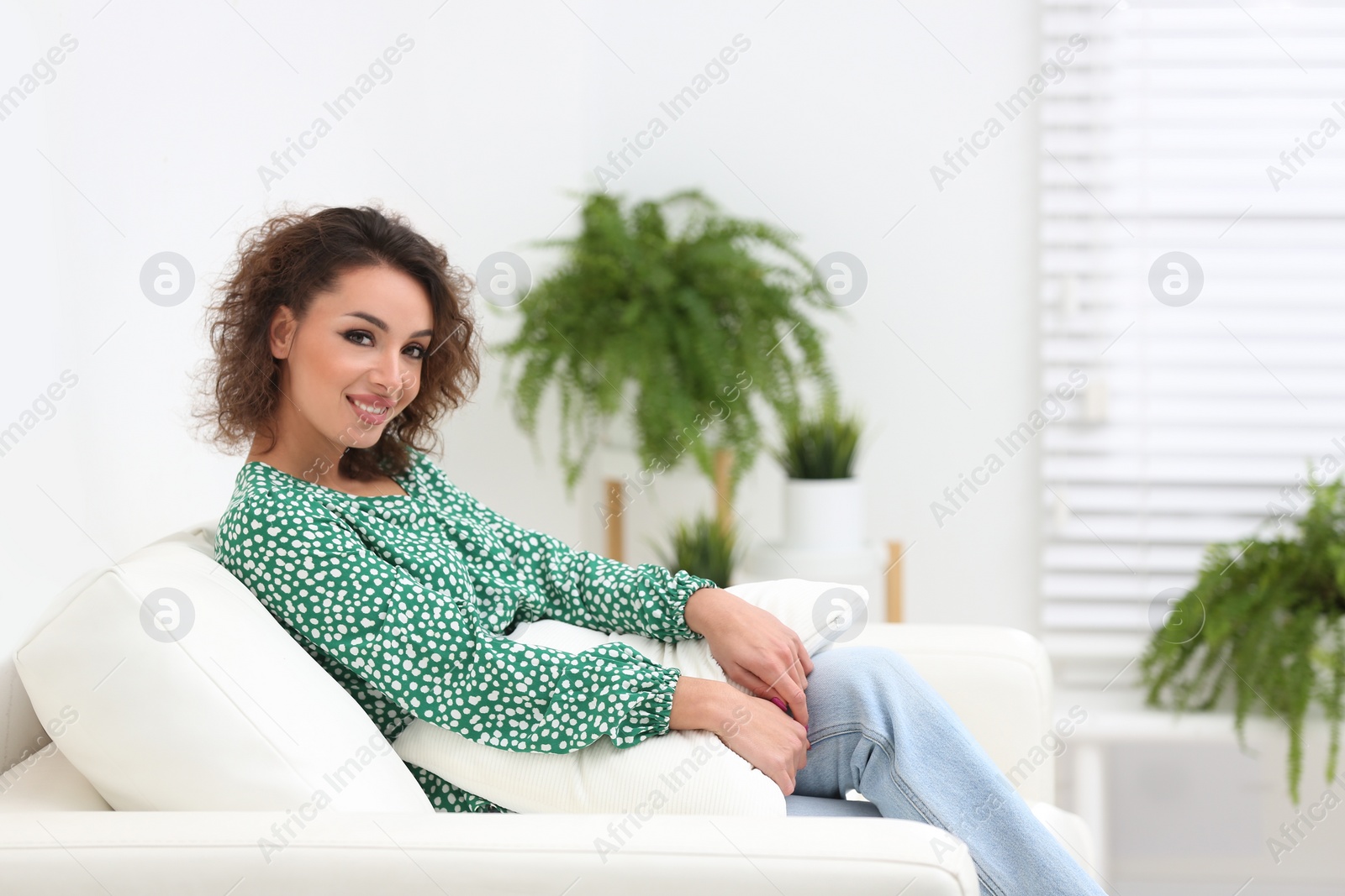 Photo of Beautiful woman in casual outfit on sofa indoors. Space for text