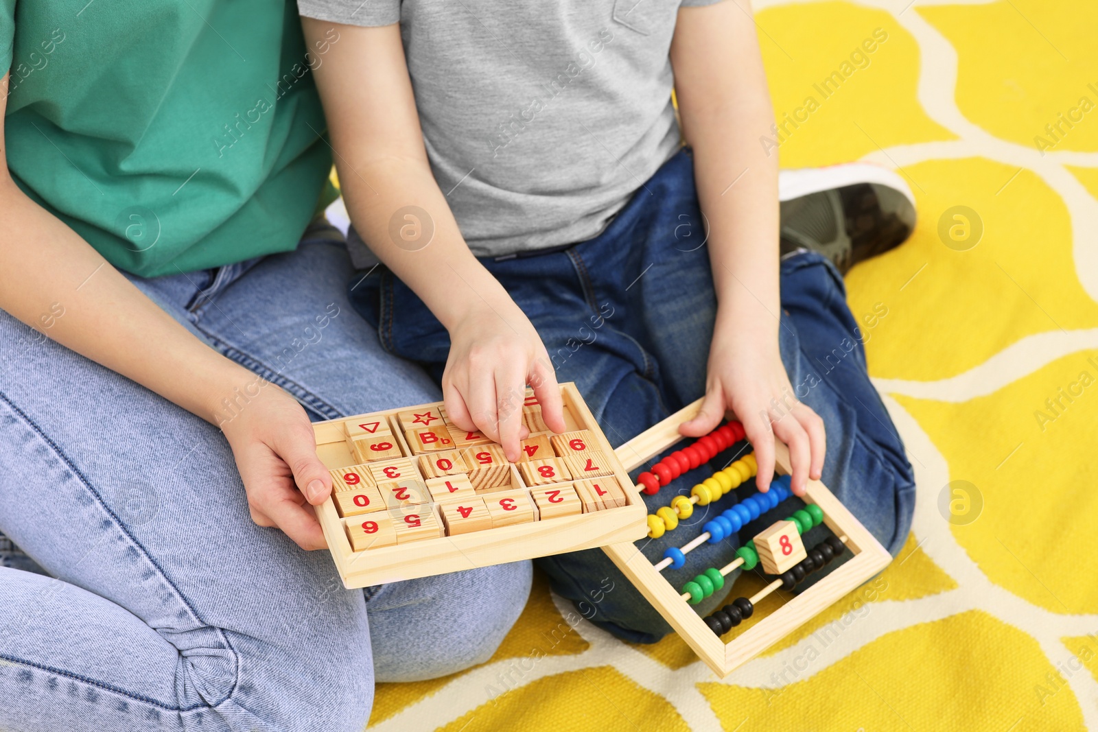 Photo of Mother and son playing with different math game kits on floor, closeup. Study mathematics with pleasure