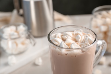 Tasty hot chocolate with milk and marshmallows in glass cup on table, closeup. Space for text