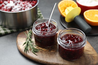 Photo of Fresh cranberry sauce in glass jars served on gray table, closeup