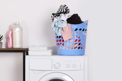 Laundry basket overfilled with clothes on washing machine in bathroom