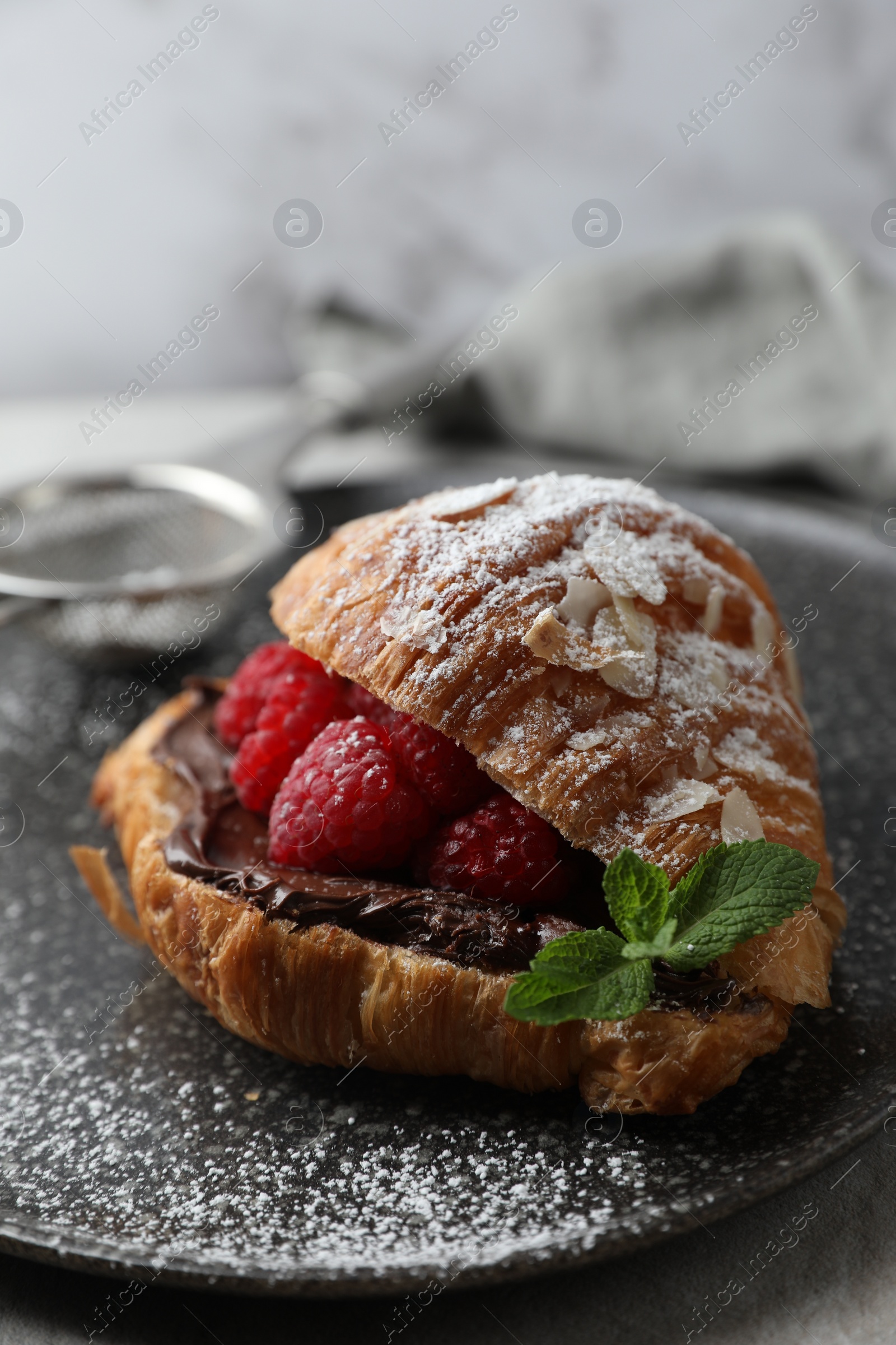 Photo of Delicious croissant with raspberries, chocolate and mint on table, closeup