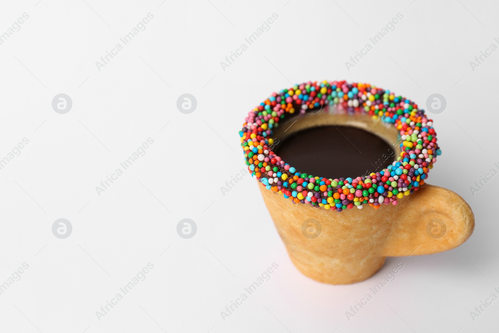 Photo of Delicious edible biscuit cup of coffee decorated with sprinkles on white background, space for text