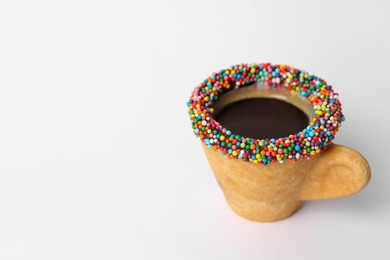 Photo of Delicious edible biscuit cup of coffee decorated with sprinkles on white background, space for text