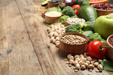 Different vegetables, seeds and fruits on wooden table, space for text. Healthy diet