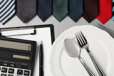 Photo of Business lunch concept. Plate, cutlery, stationery and ties on light gray table, flat lay