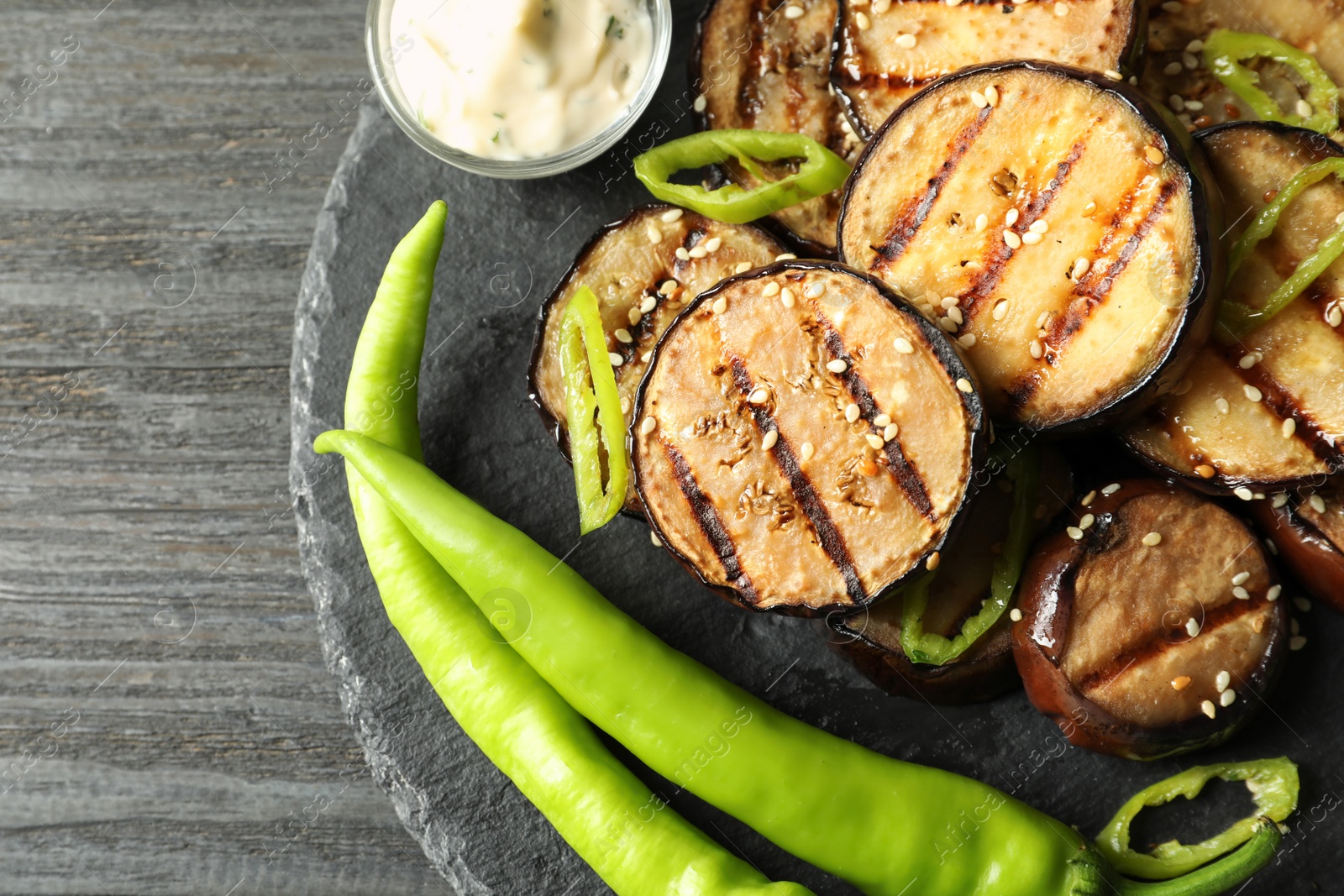 Photo of Slate plate with fried eggplant slices on wooden table, top view