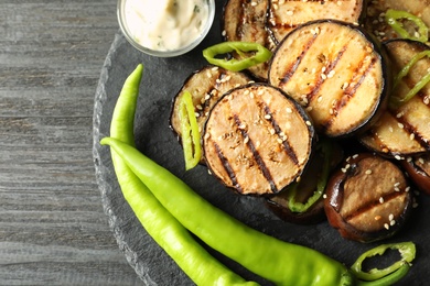 Slate plate with fried eggplant slices on wooden table, top view