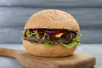 Photo of Delicious cheeseburger with lettuce, onion, ketchup and patty on table, closeup