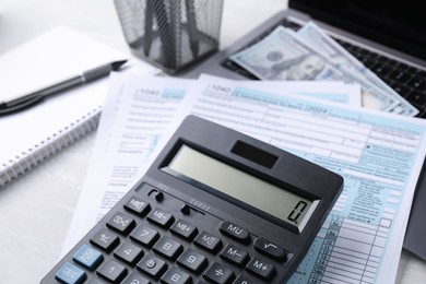 Photo of Tax accounting. Calculator, documents, money and stationery on light grey table, closeup