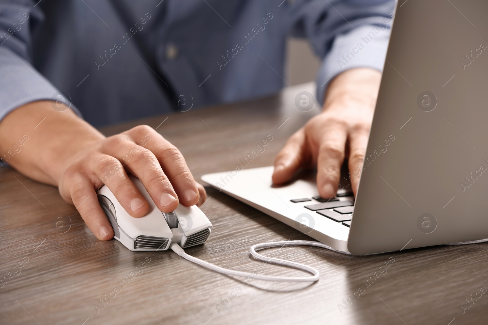 Photo of Man using computer mouse with laptop at table, closeup