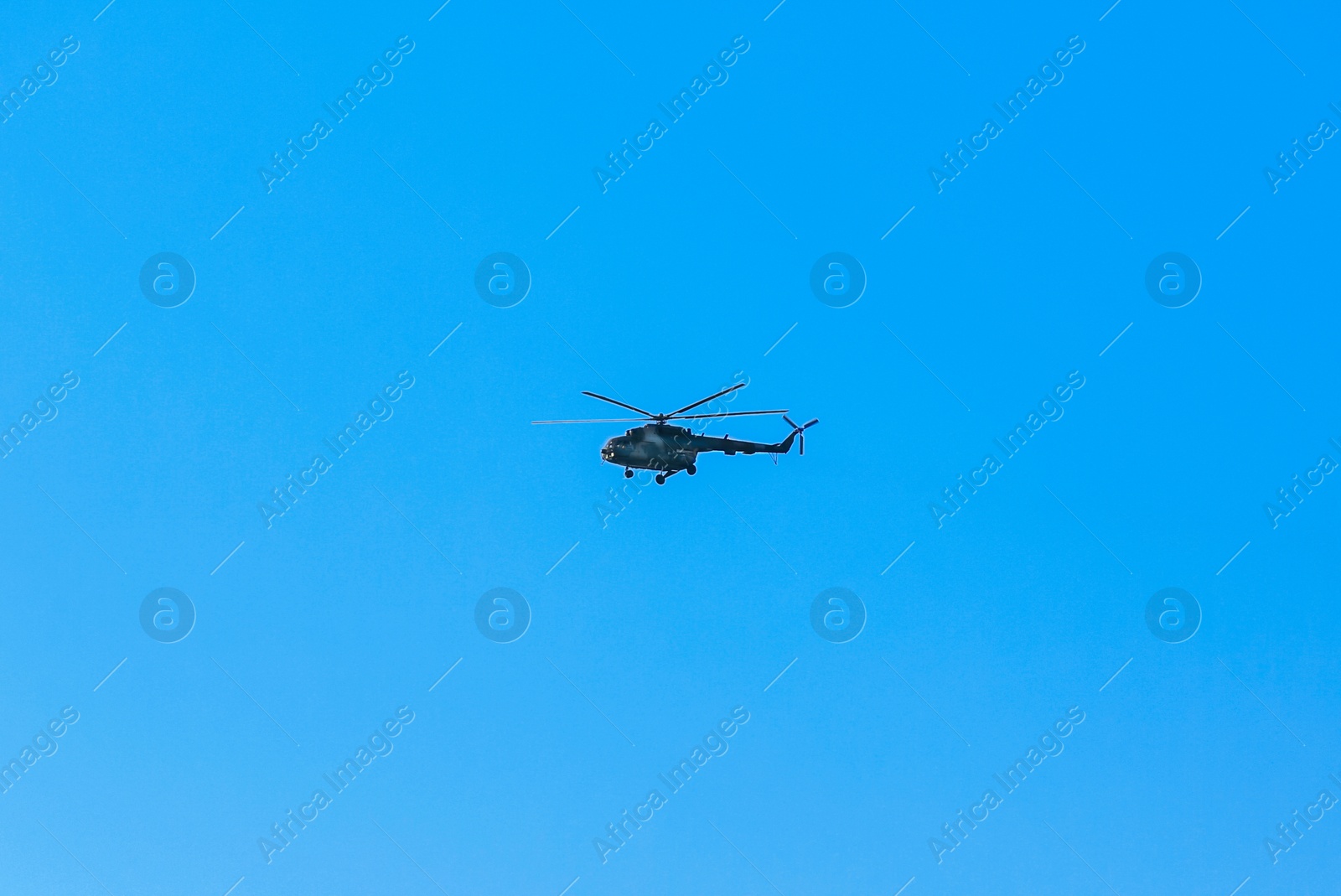 Photo of Modern military helicopter flying in blue sky