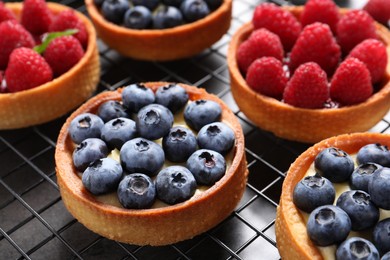 Tartlets with different fresh berries on cooling rack, closeup. Delicious dessert