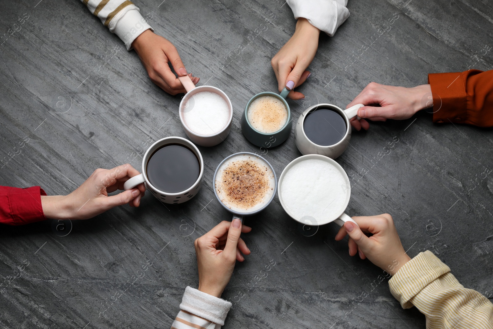 Photo of People holding different cups with aromatic hot coffee at grey table, top view